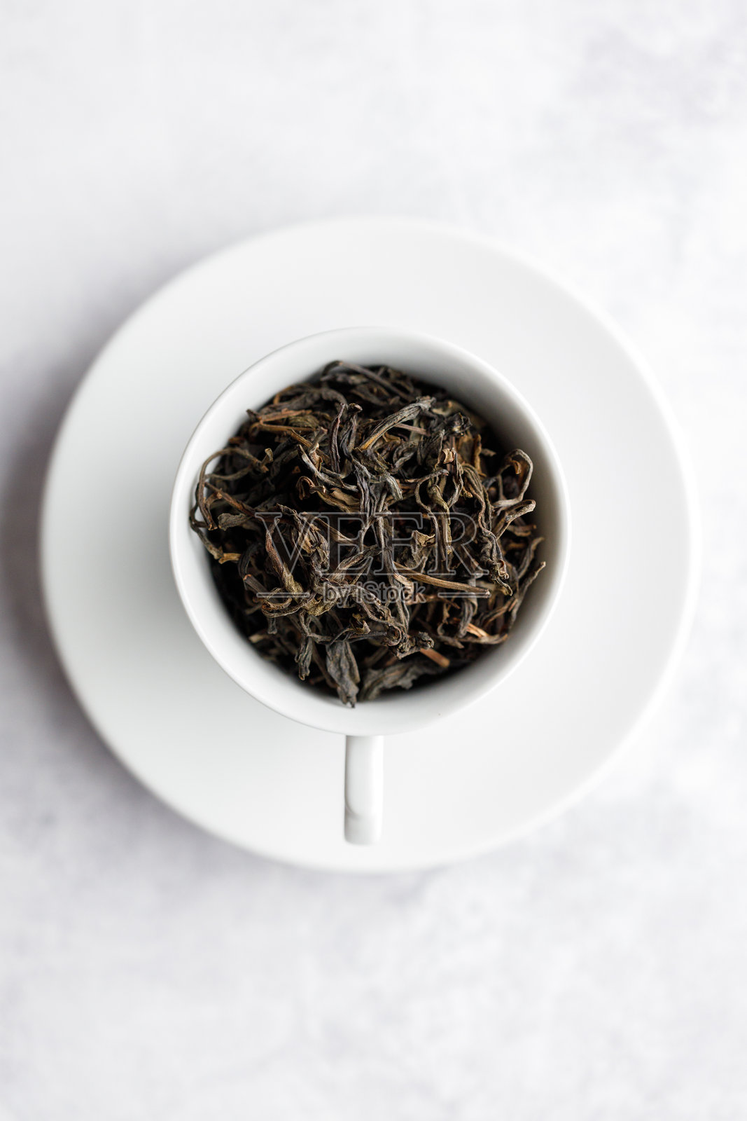 白色桌面上的一杯热茶，杯中盛满茶叶。照片摄影图片