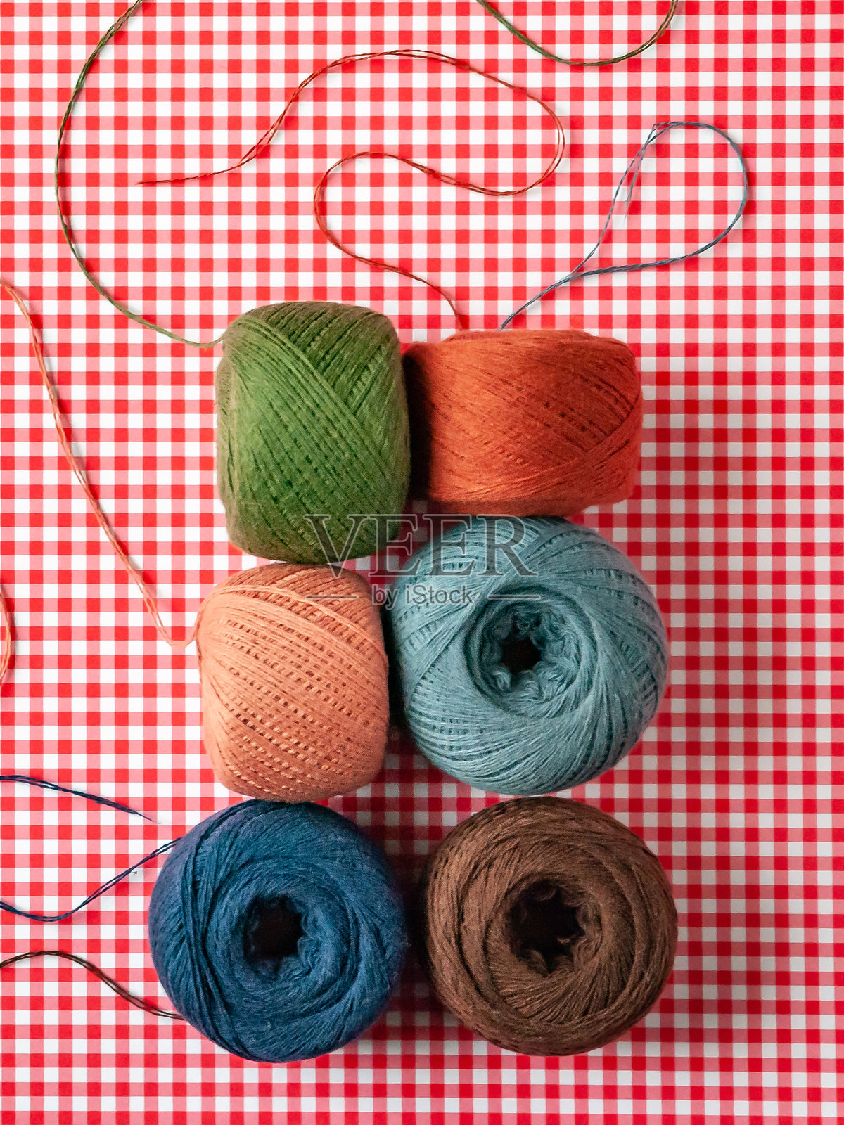 红色格子背景上的多彩棉线卷照片摄影图片