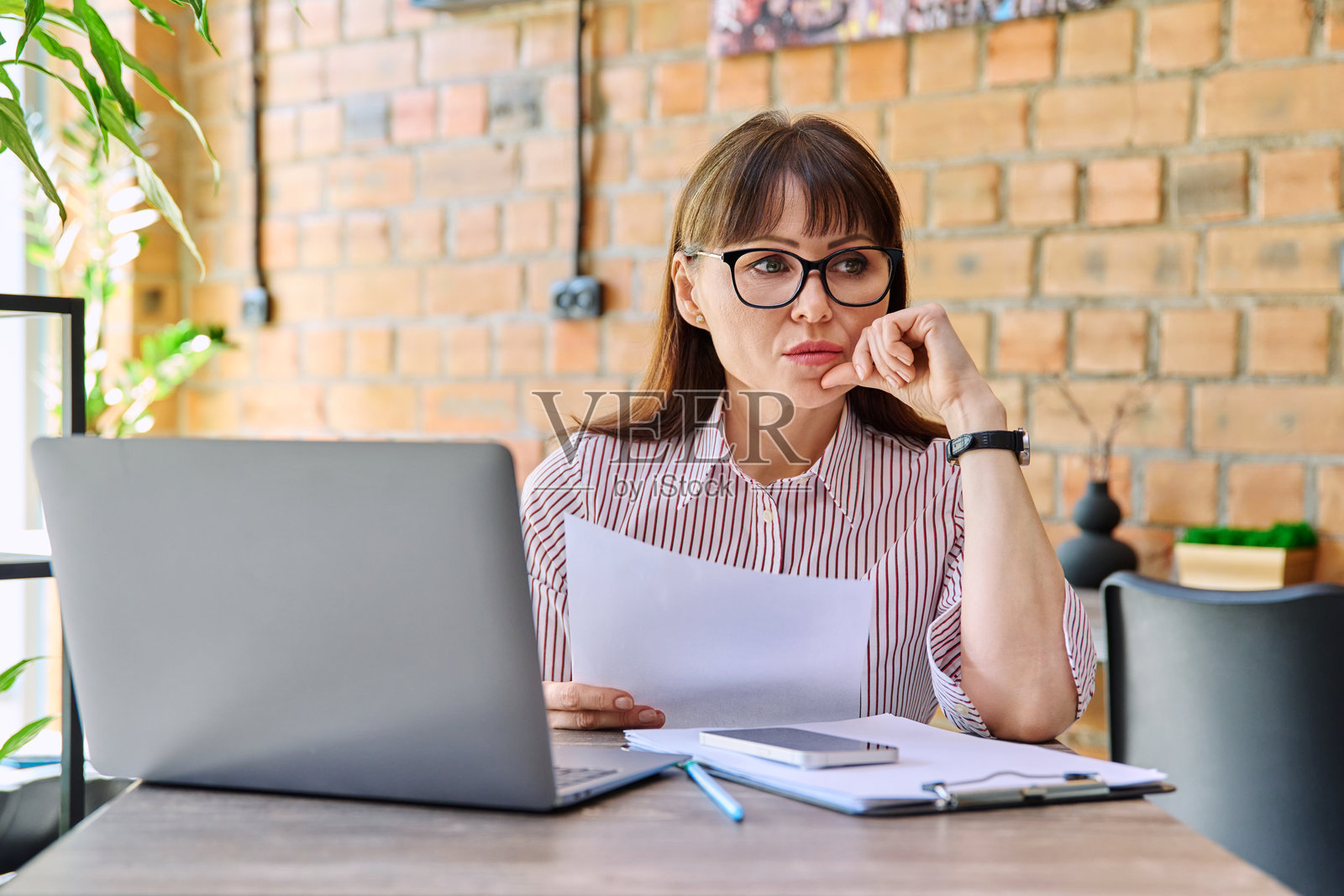 严肃而伤感的中年女商人在共享办公咖啡馆阅读纸质信件照片摄影图片