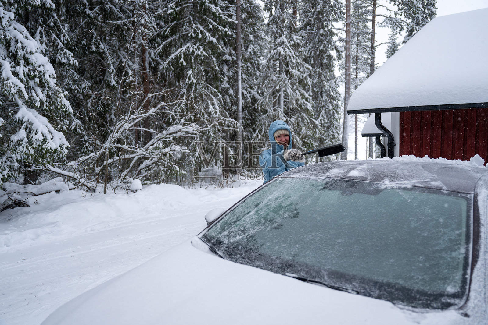 女人用刷子清除汽车上的雪。洗车概念。照片摄影图片