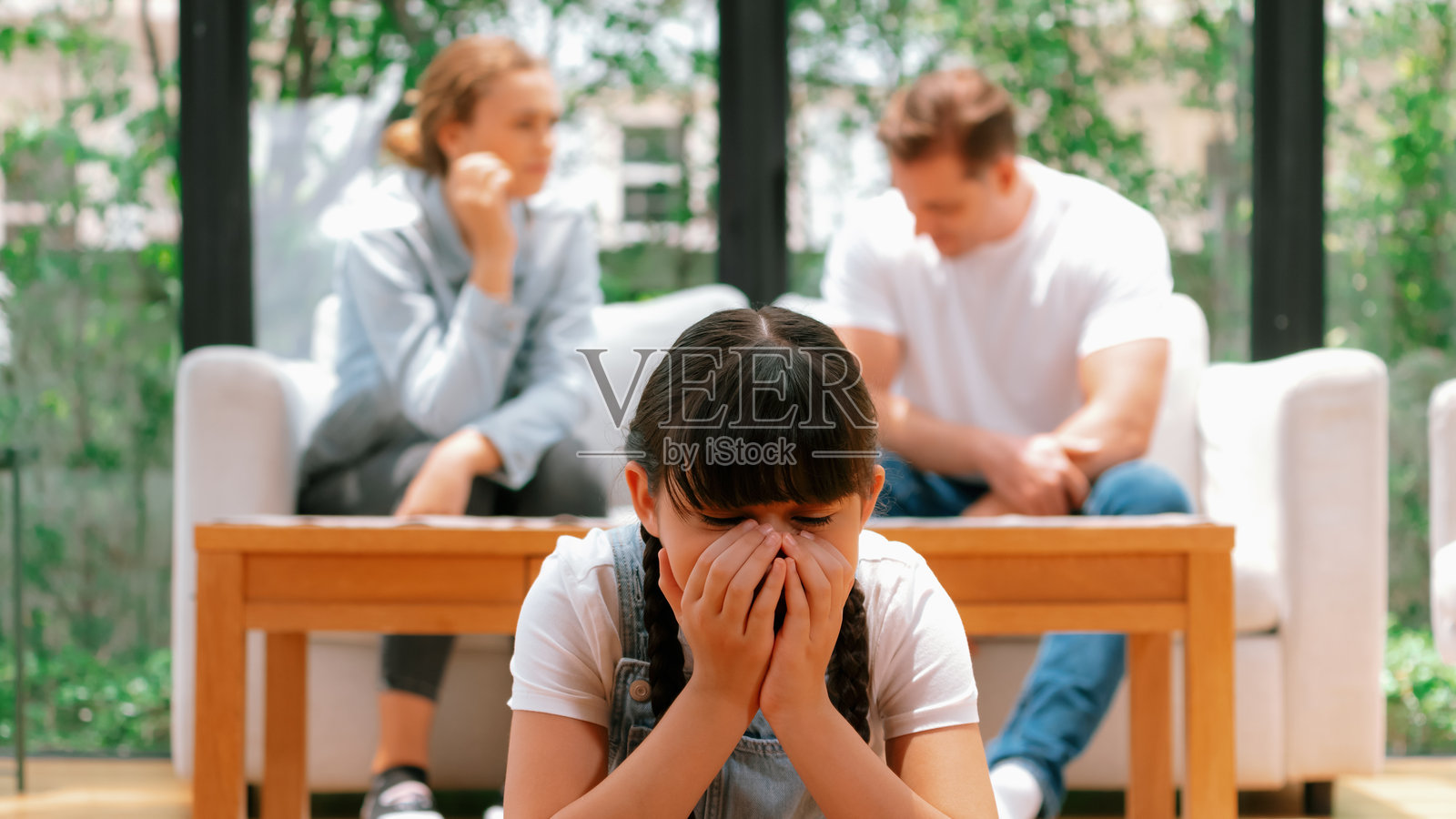 年轻女孩被父母争吵的紧张气氛所困扰。照片摄影图片