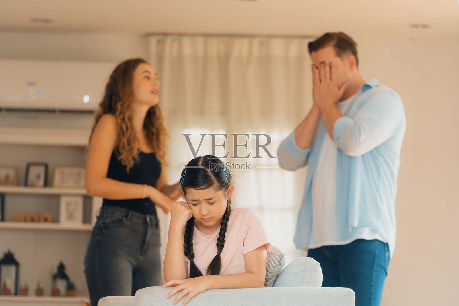 年轻女孩被父母争吵的紧张气氛所困扰。照片摄影图片