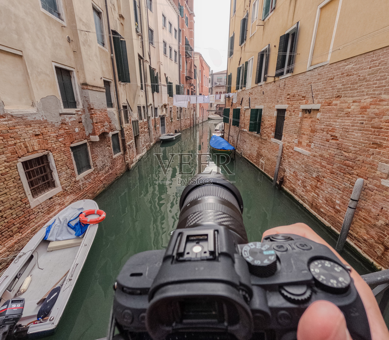 从上方俯视拍摄威尼斯狭窄运河的相机。照片摄影图片