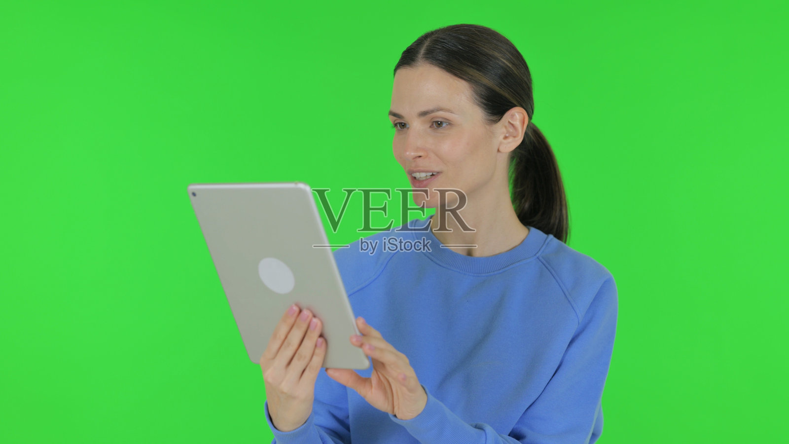在绿色背景下用平板电脑进行视频聊天的女性照片摄影图片