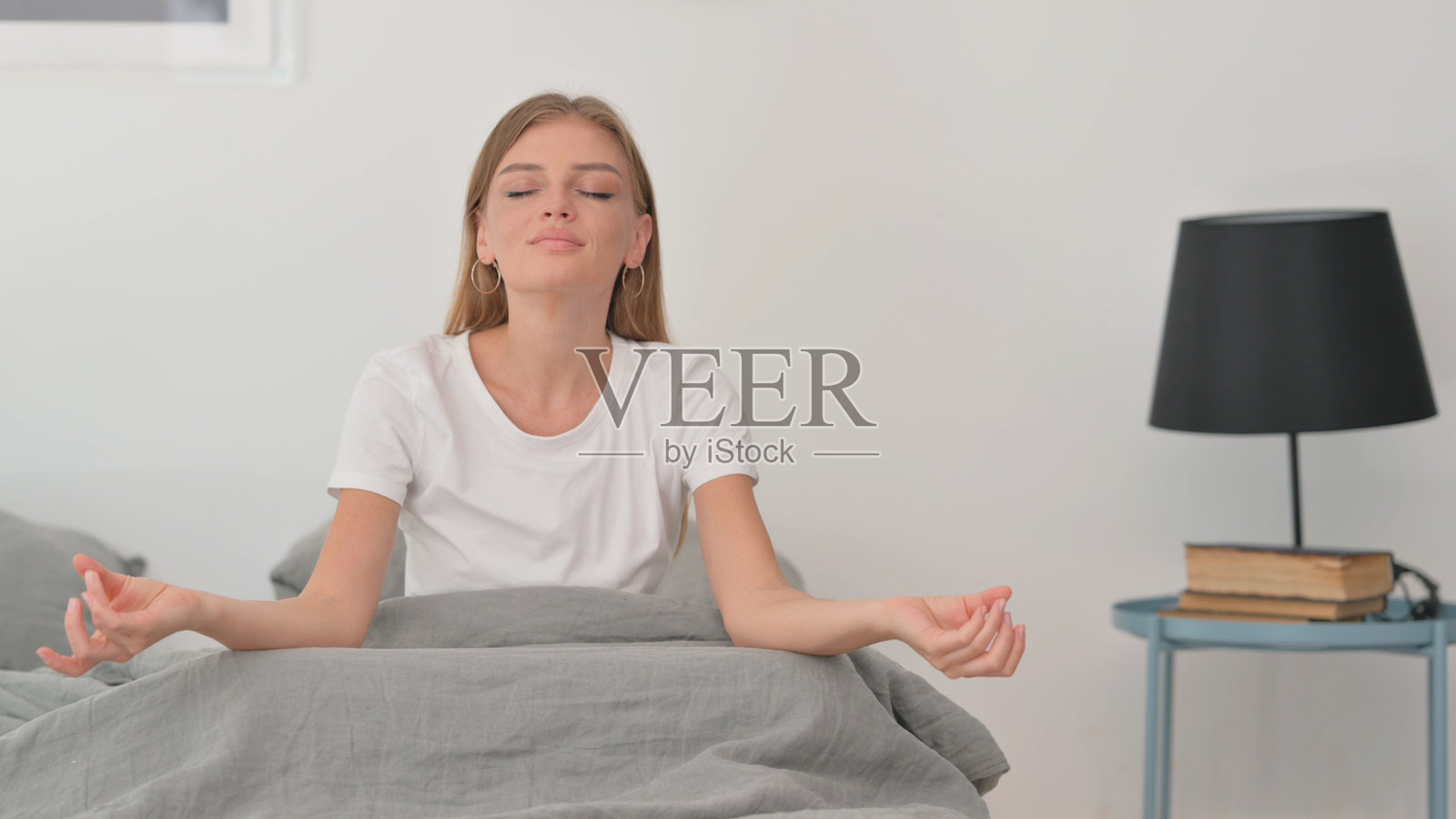 年轻女性坐在床上做瑜伽照片摄影图片