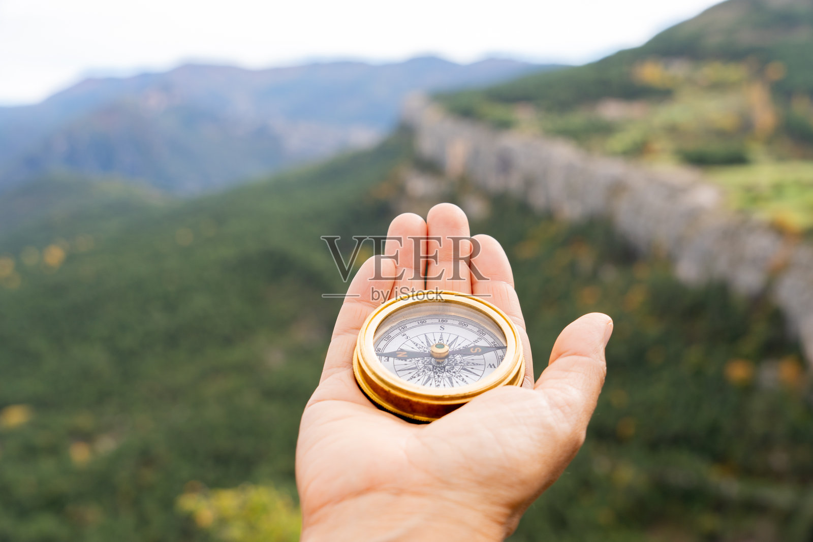 手握指南针在崎岖的山地地形中导航，展现了荒野探索和户外导航的旅程照片摄影图片
