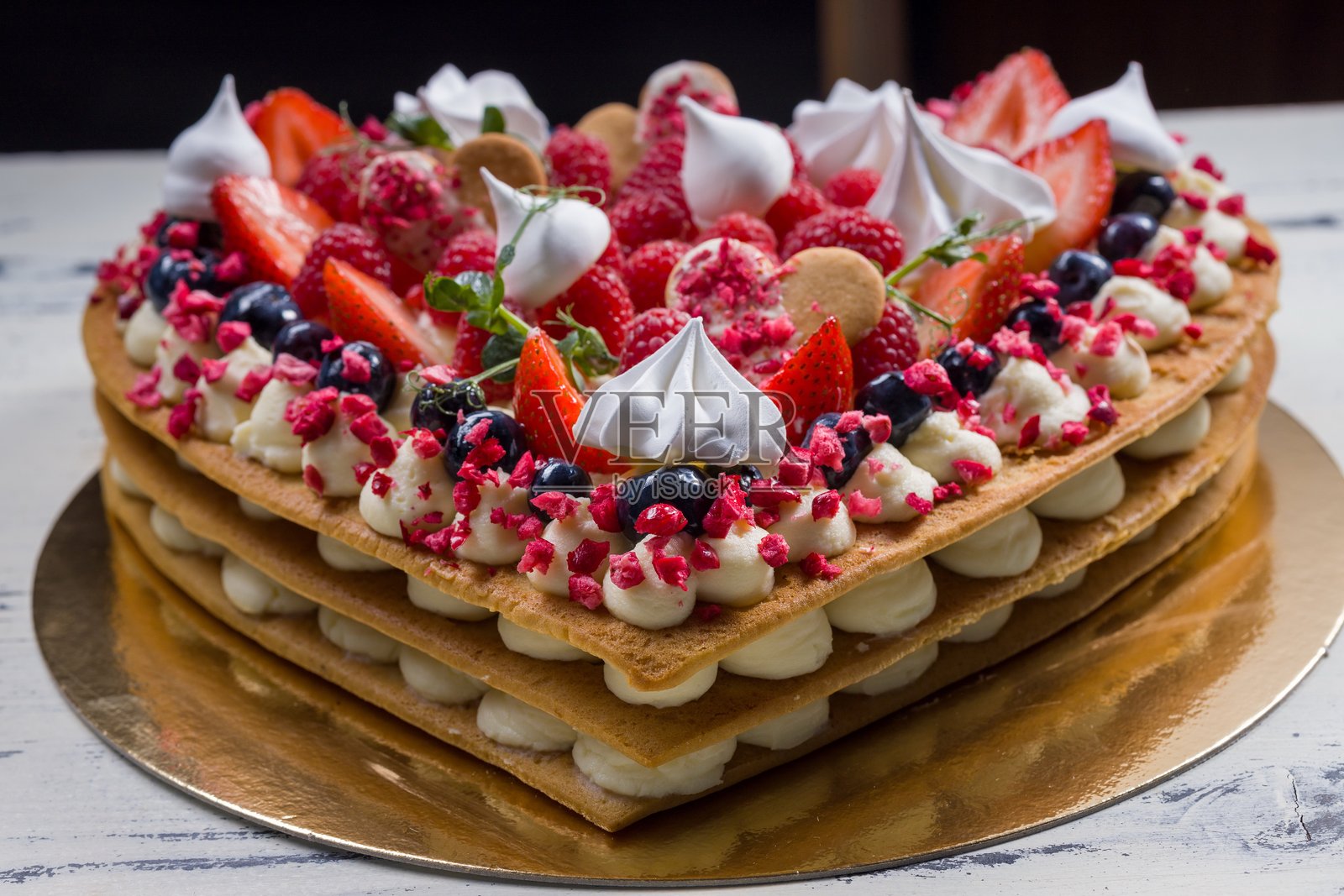 优雅的心形蛋糕，上面装饰着新鲜浆果、奶油和蛋白霜。照片摄影图片