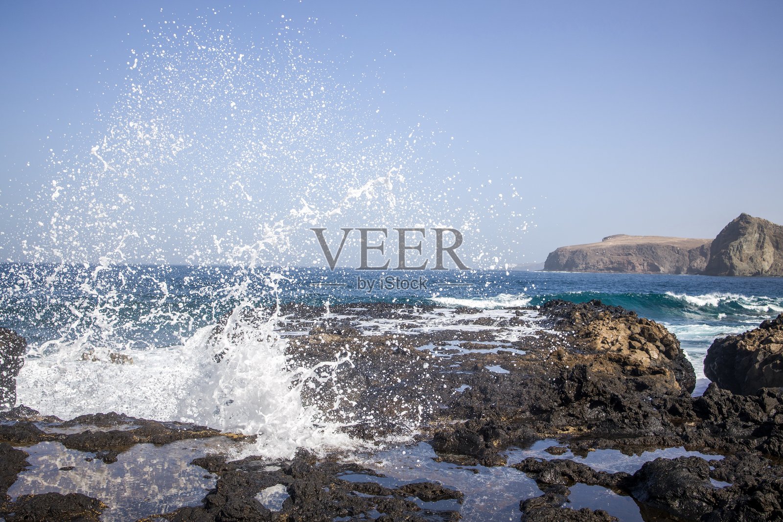 在大加那利岛，海浪拍打着岩石海岸。照片摄影图片