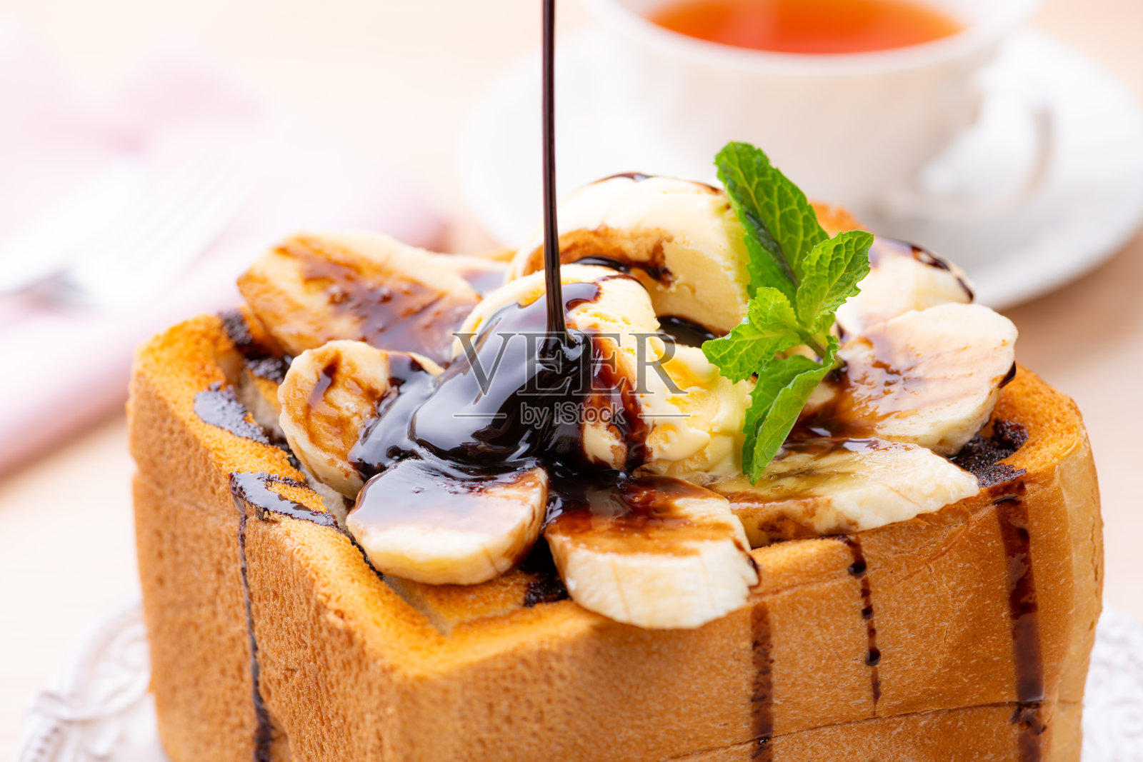 蜂蜜吐司，上面放有香草冰淇淋、香蕉和巧克力酱淋。照片摄影图片
