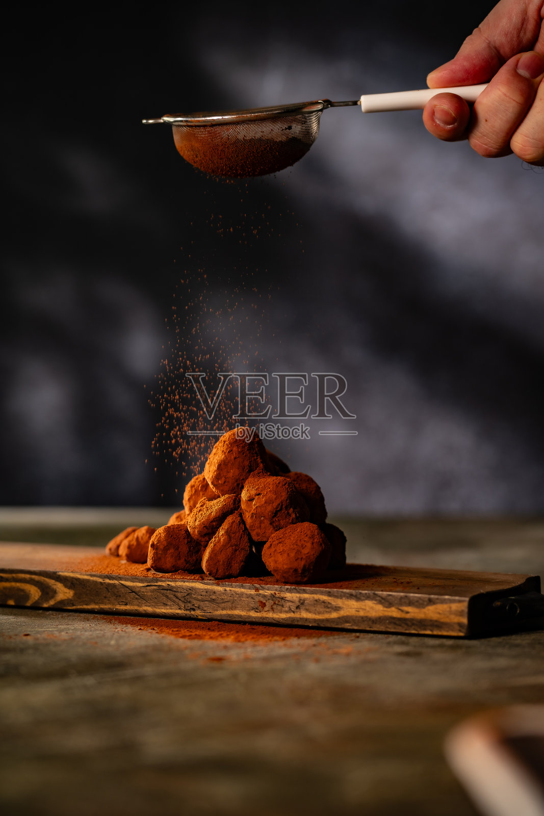 美味的巧克力松露撒上可可粉放在桌子上。照片摄影图片