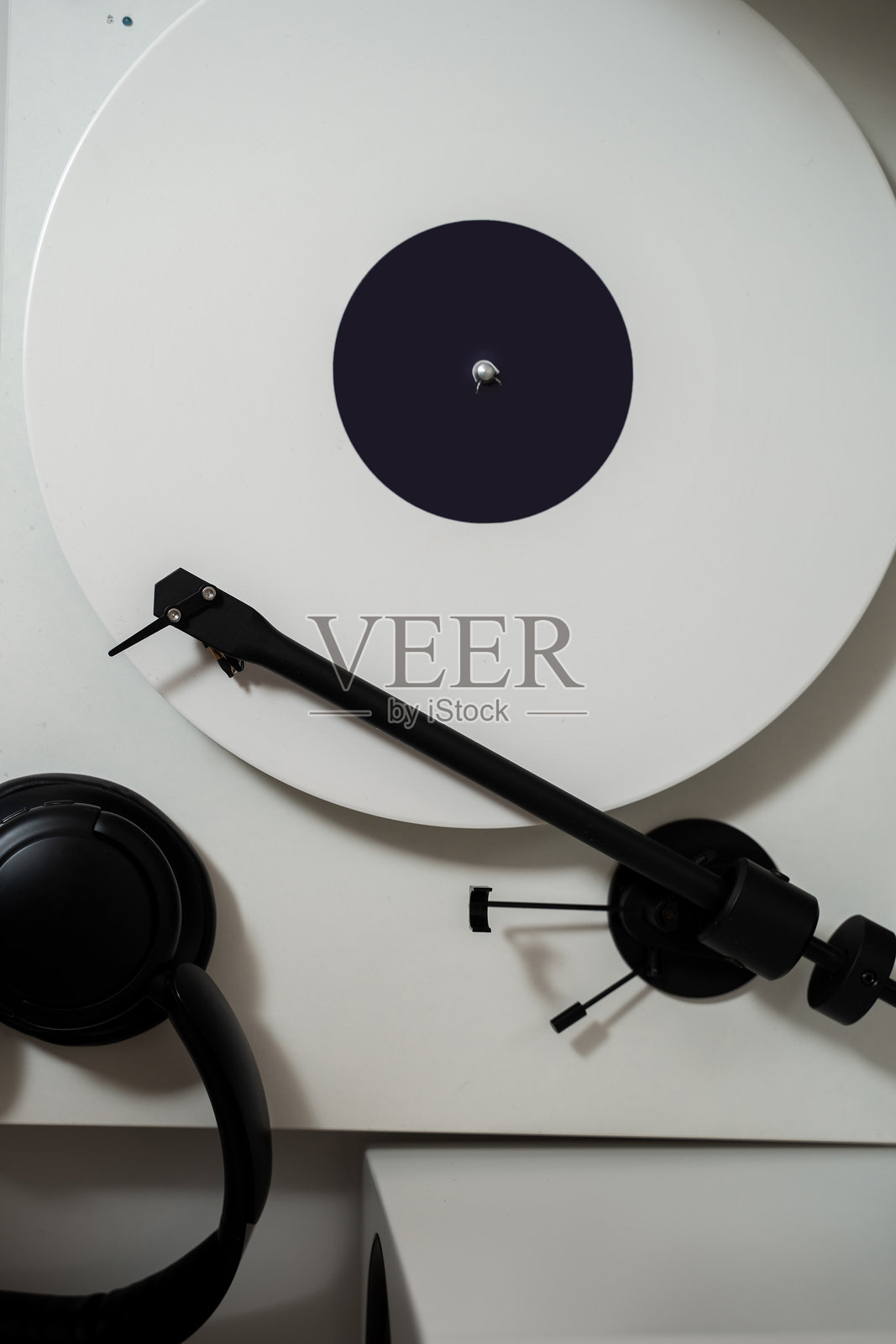 33转白色乙烯基唱片在唱针播放器上，配有耳机音响。通过音响系统享受高保真音质的音乐。照片摄影图片