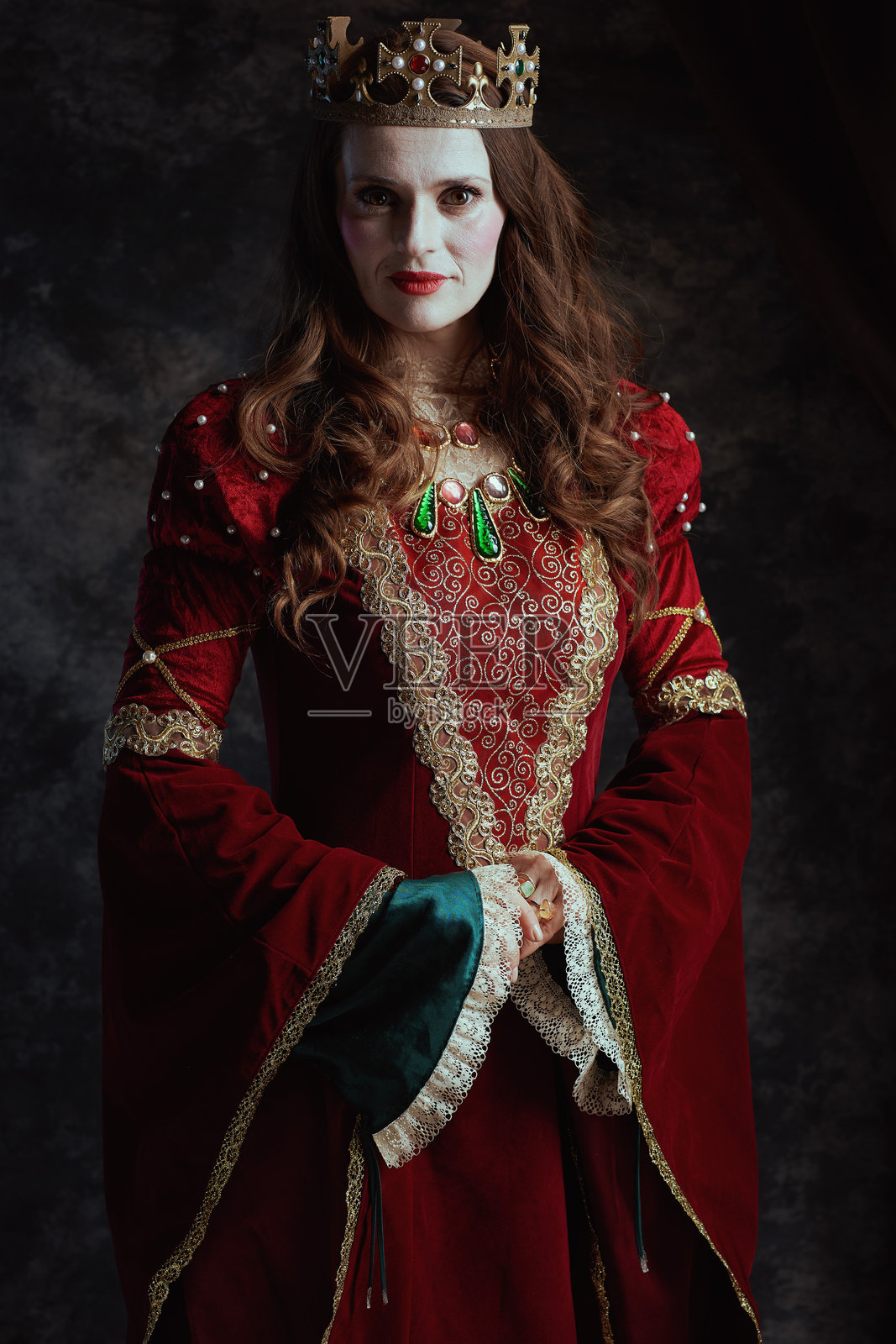 穿着红色裙子、涂着白色妆容并戴着王冠的中世纪女王照片摄影图片