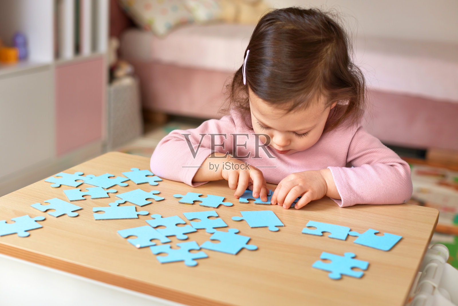 孩子在房间的木桌上拼接拼图块照片摄影图片