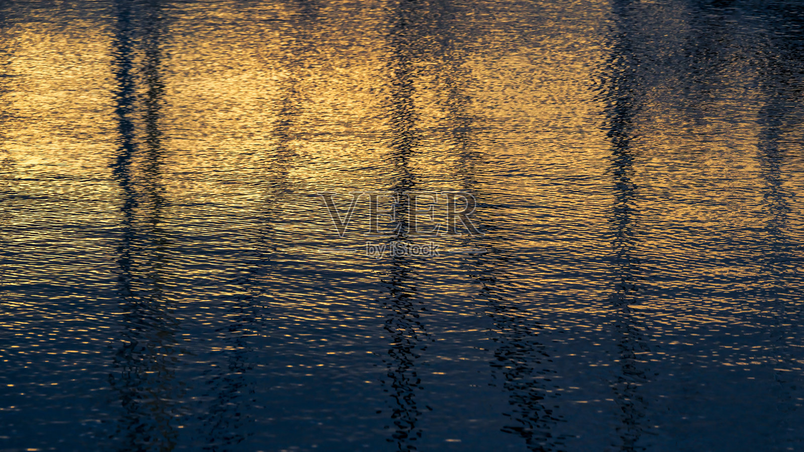 宁静水面上金色日落的倒影与平静涟漪照片摄影图片