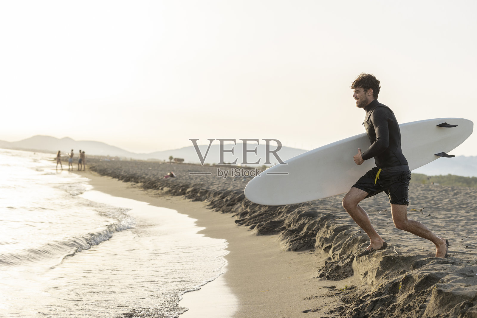 冲浪者在日落时奔向海浪照片摄影图片