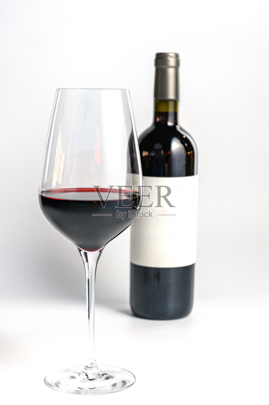 白色背景上的红酒杯与酒瓶。照片摄影图片