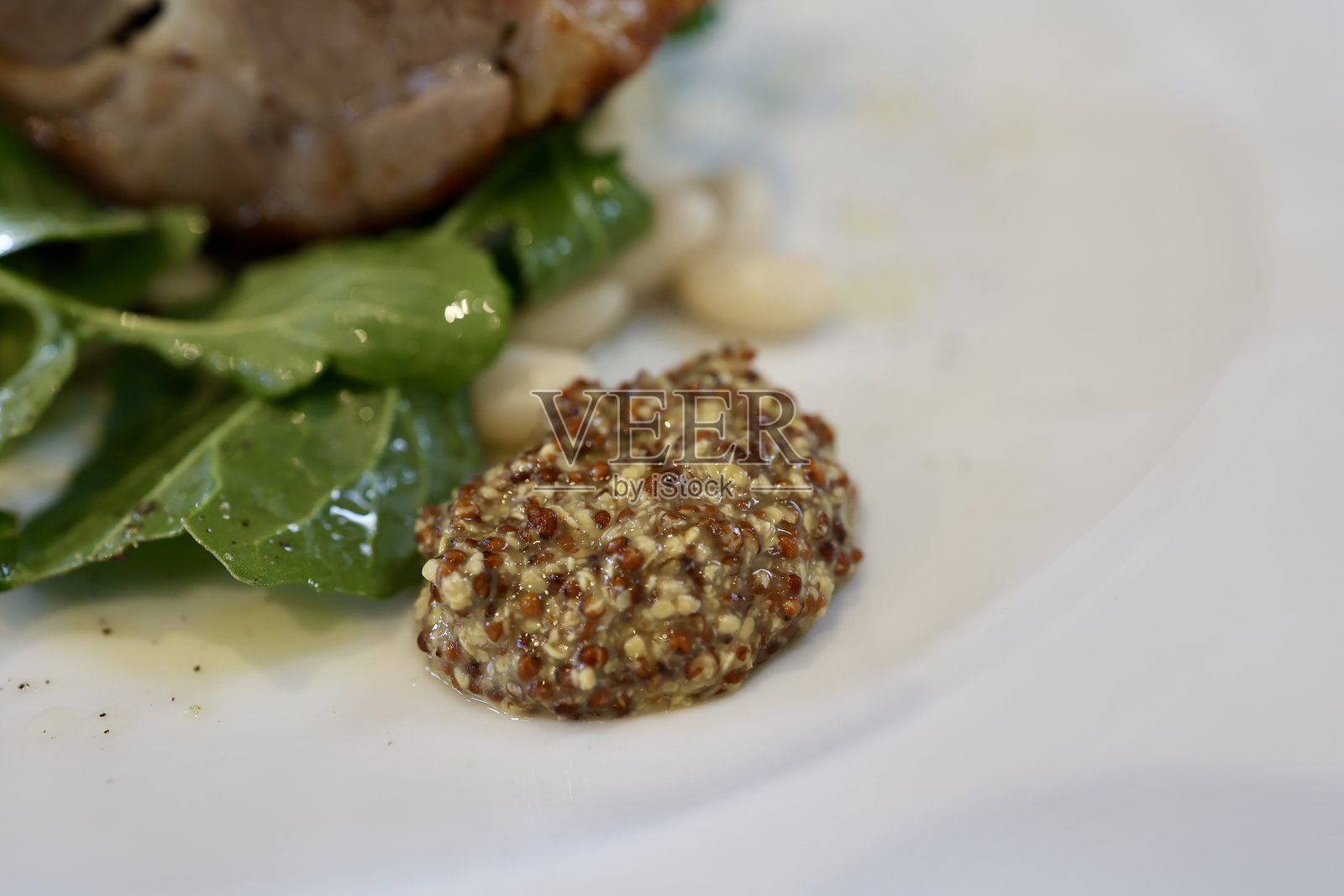 与肉类菜肴搭配的芥末粒。照片摄影图片