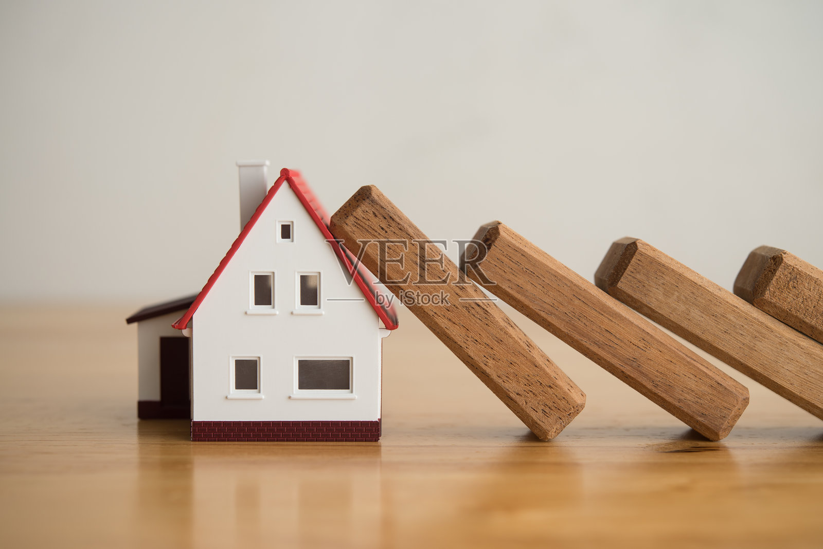 多米诺骨牌效应导致房子倒塌在木桌上。照片摄影图片