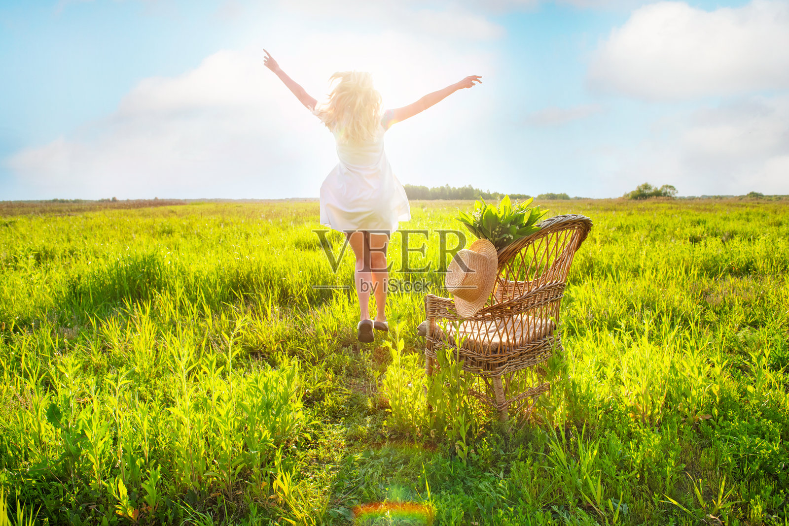 一个女孩在绿色的田野上跳跃着向远方奔跑。背影视角。快乐的活跃女性在大自然中。照片摄影图片