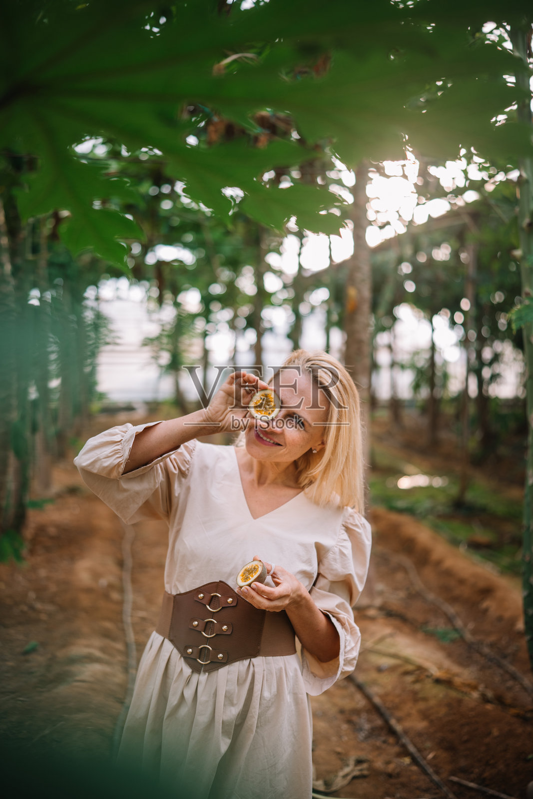 女人在阳光明媚的下午，在郁郁葱葱的花园中享受新鲜水果照片摄影图片