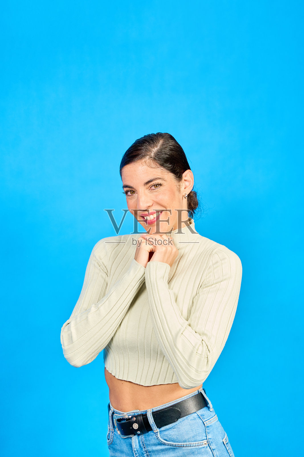 年轻女性微笑着，双手交叉在蓝色背景前照片摄影图片