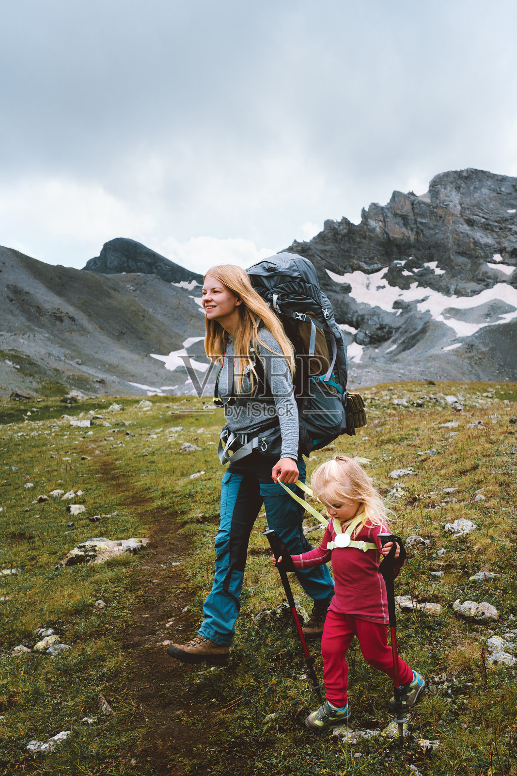 家庭在山中徒步旅行，母亲与孩子一起享受积极的冒险之旅，健康的生活方式，户外活动，孩子使用登山杖和安全带装备攀爬。照片摄影图片