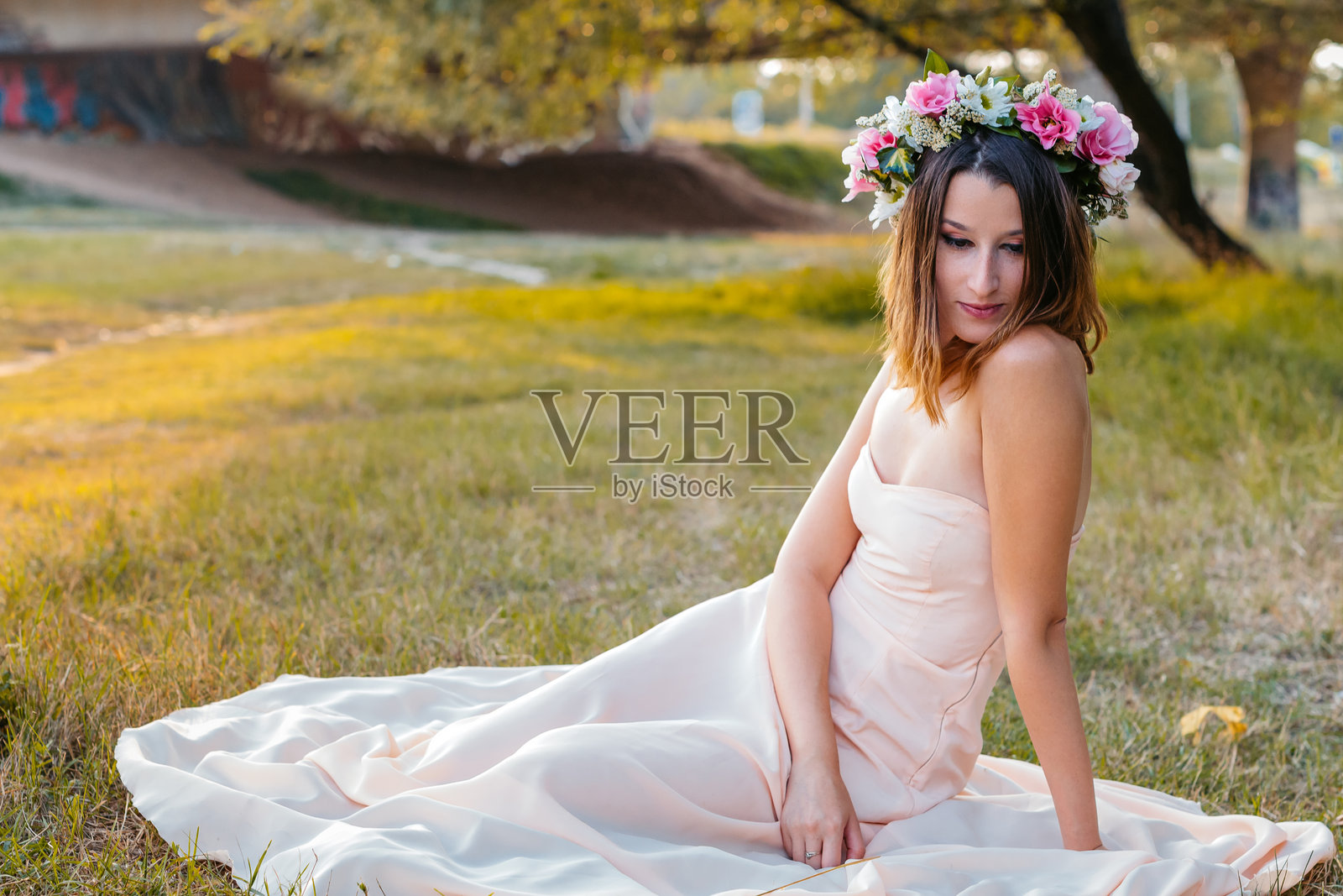 年轻女性坐在田野中，头戴花冠照片摄影图片