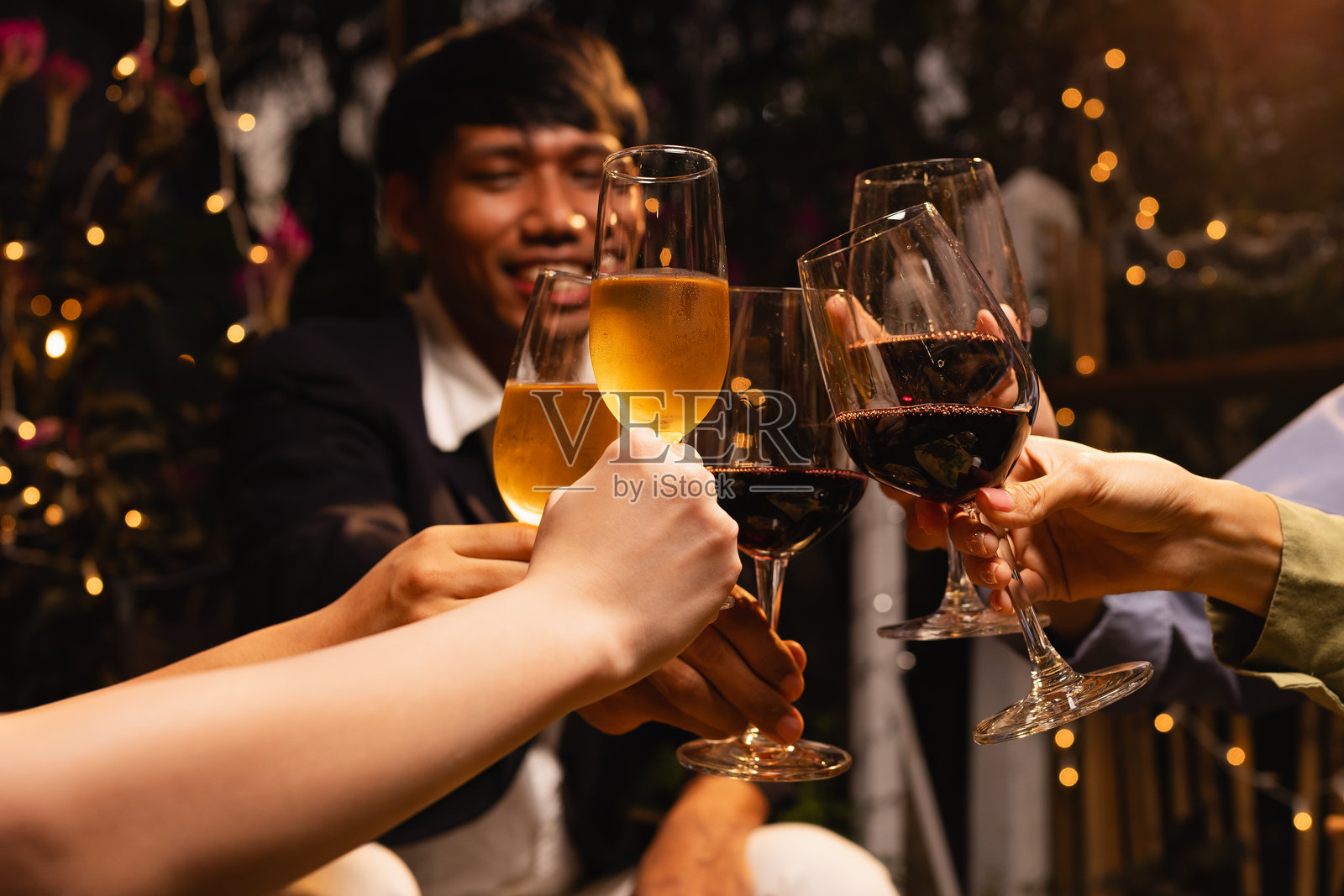 一群朋友在夜晚派对上碰杯庆祝。照片摄影图片