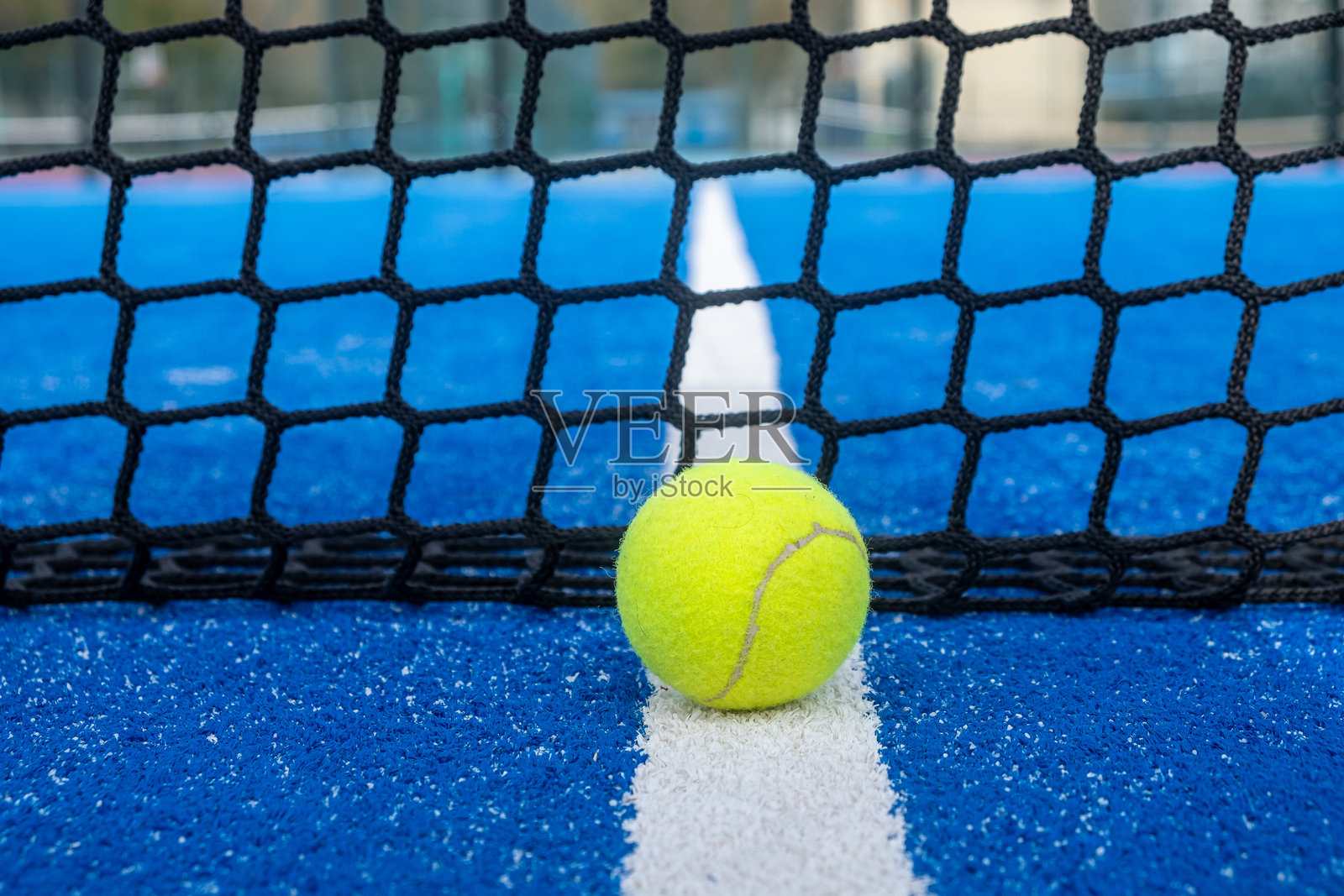 在蓝色的乒乓球场上，网前的界线上放着一个球，背景是球拍运动的概念。照片摄影图片