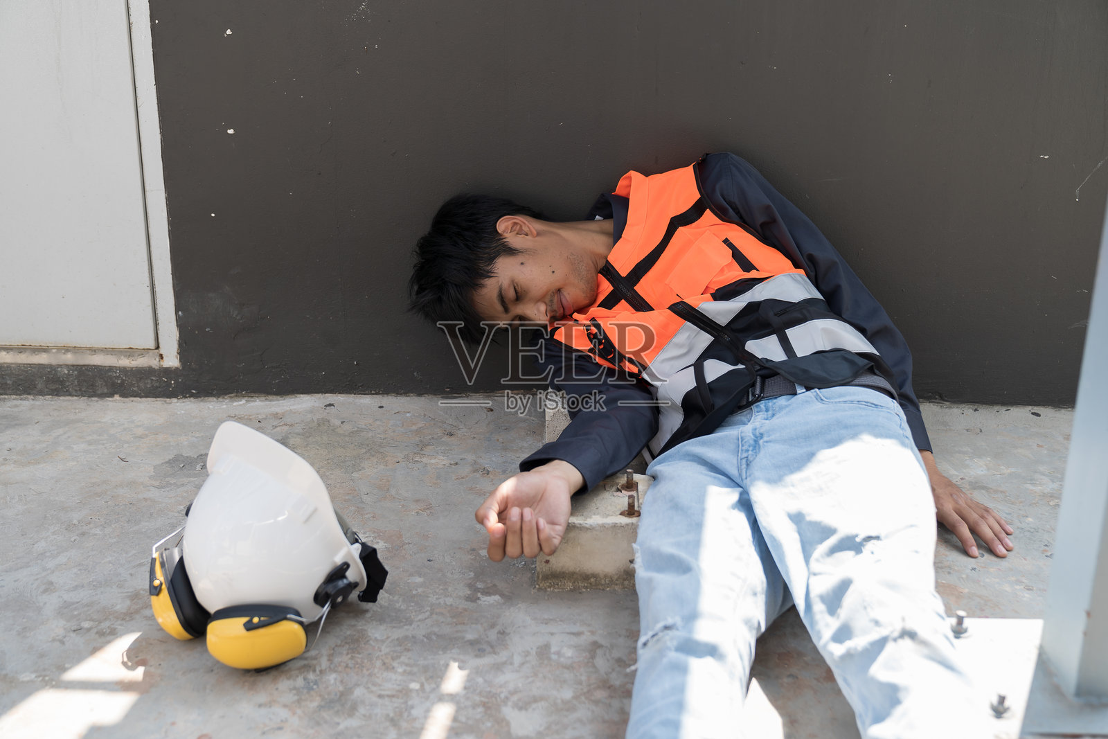 亚洲男性工人在建筑工地发生事故。建筑工人感到不适，头痛。健康安全和安全第一的理念。照片摄影图片