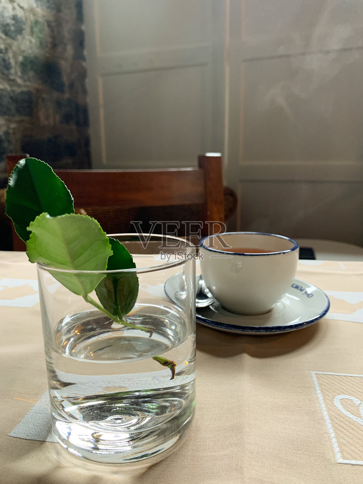 一杯水的特写，水面上漂浮着一片茶叶，旁边是一杯热茶。照片摄影图片