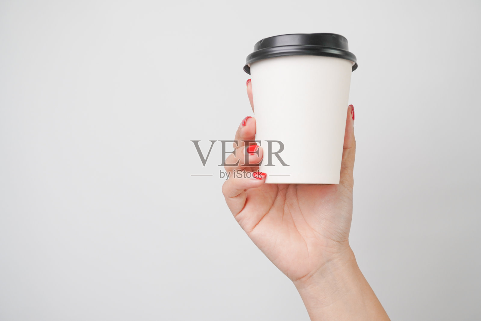 一个手握着纸质咖啡杯，背景为白色。照片摄影图片