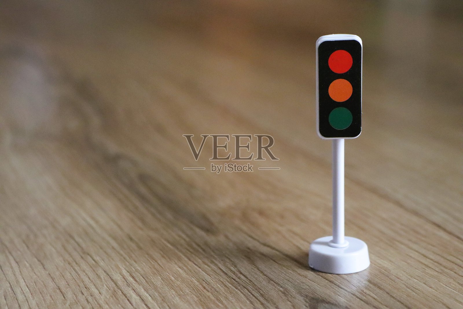 一个迷你交通信号灯模型优雅地展示在木质表面上，作为装饰用途。照片摄影图片