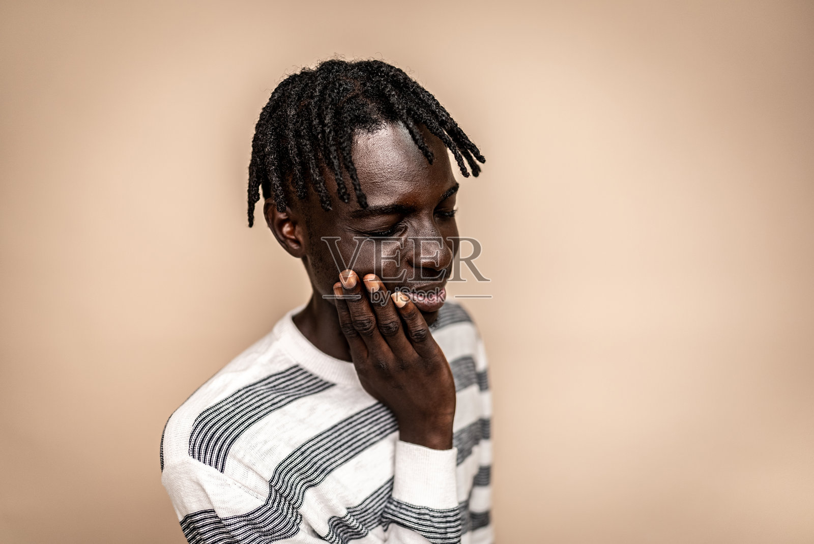 年轻男子在米色背景下感到牙痛照片摄影图片