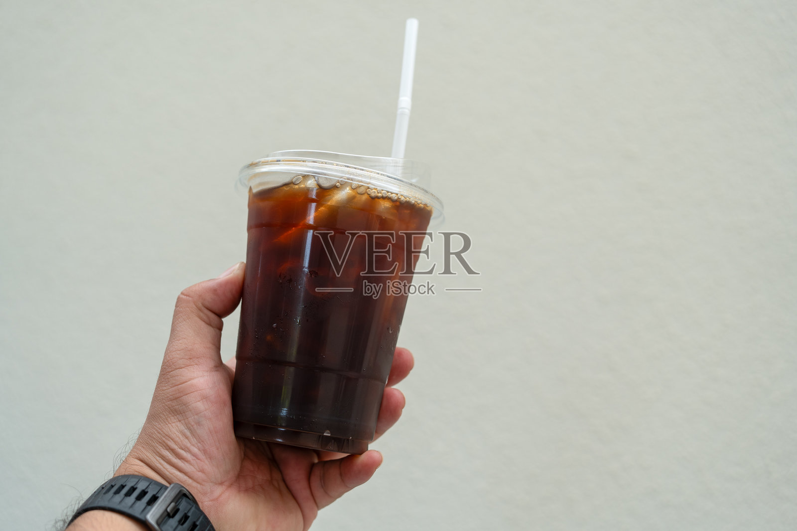 有人手里拿着一个装冰美式咖啡的塑料杯照片摄影图片