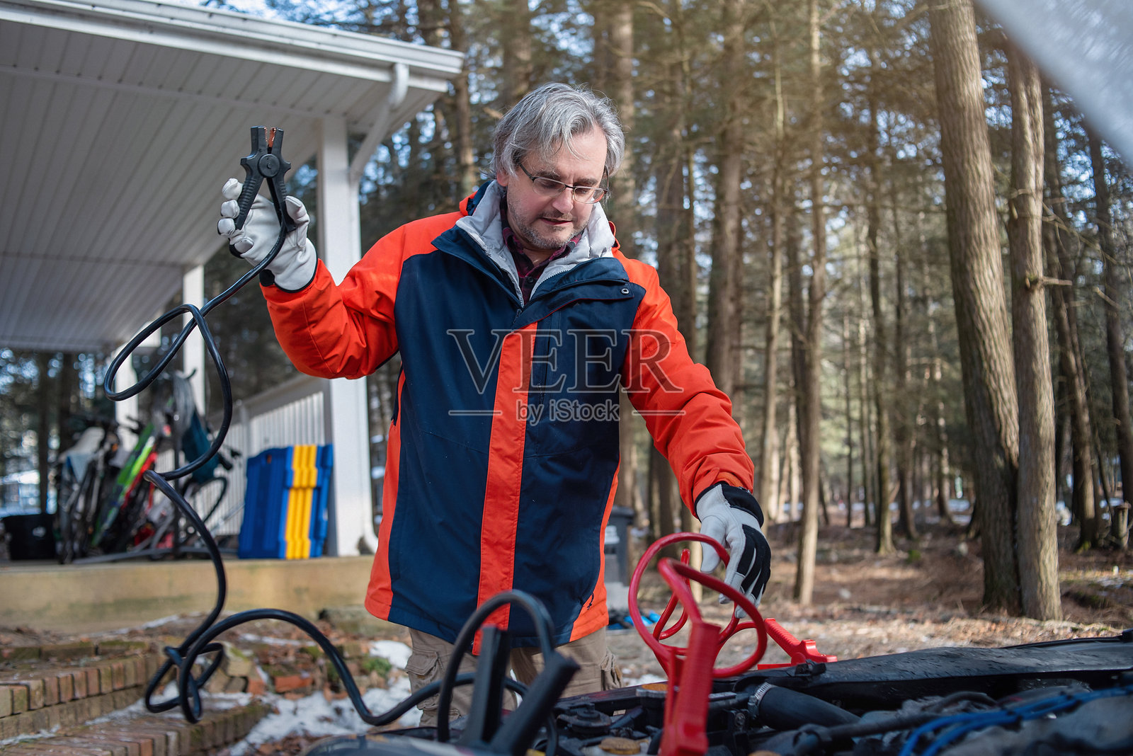 车辆主人在松树环绕的住宅外排查汽车故障照片摄影图片