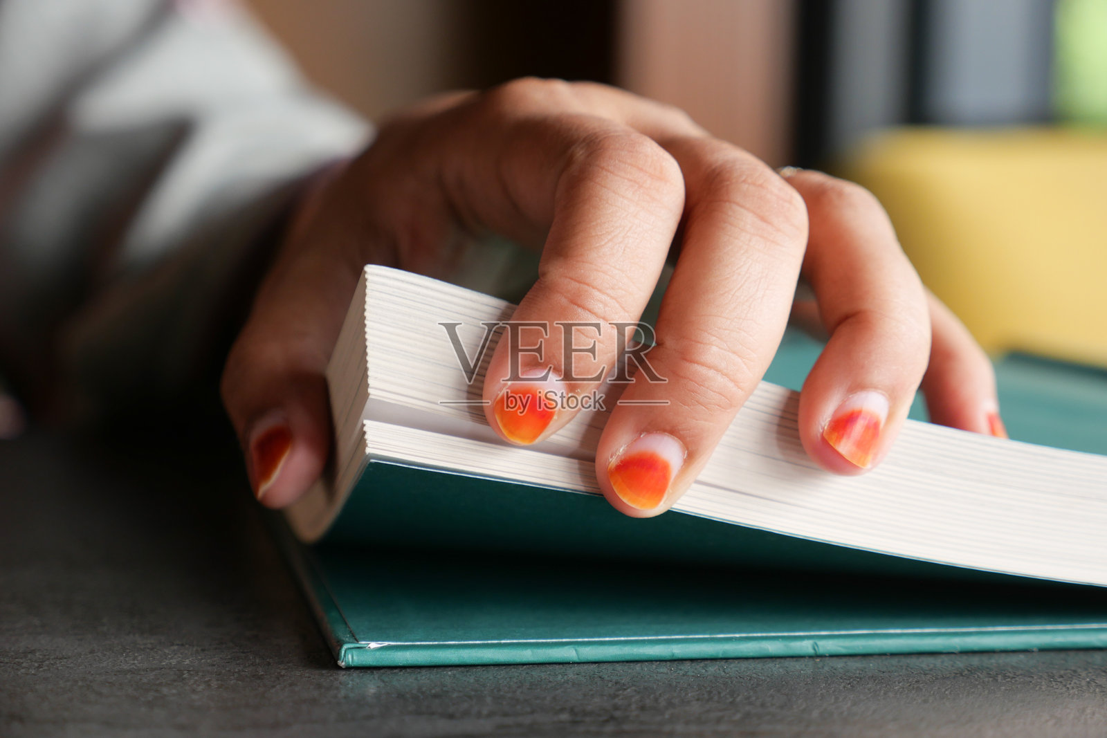 一只手轻柔地翻动一本打开书页的特写，指甲上装饰着时尚的美甲艺术照片摄影图片