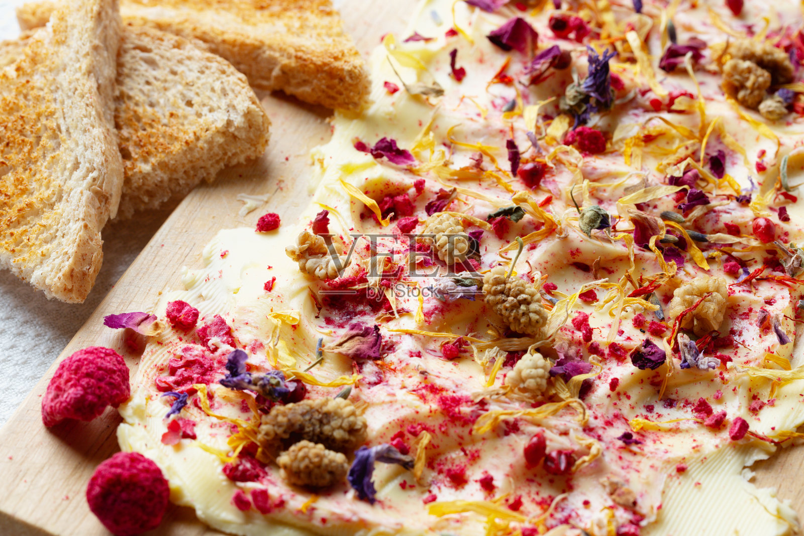 特写的水果黄油板，上面有干覆盆子和可食用花朵照片摄影图片