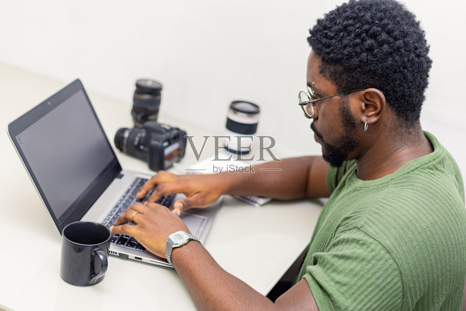 摄影师在使用笔记本电脑和数码相机。专业记者或自由职业者在桌子上使用笔记本与单反相机和摄影设备。照片摄影图片