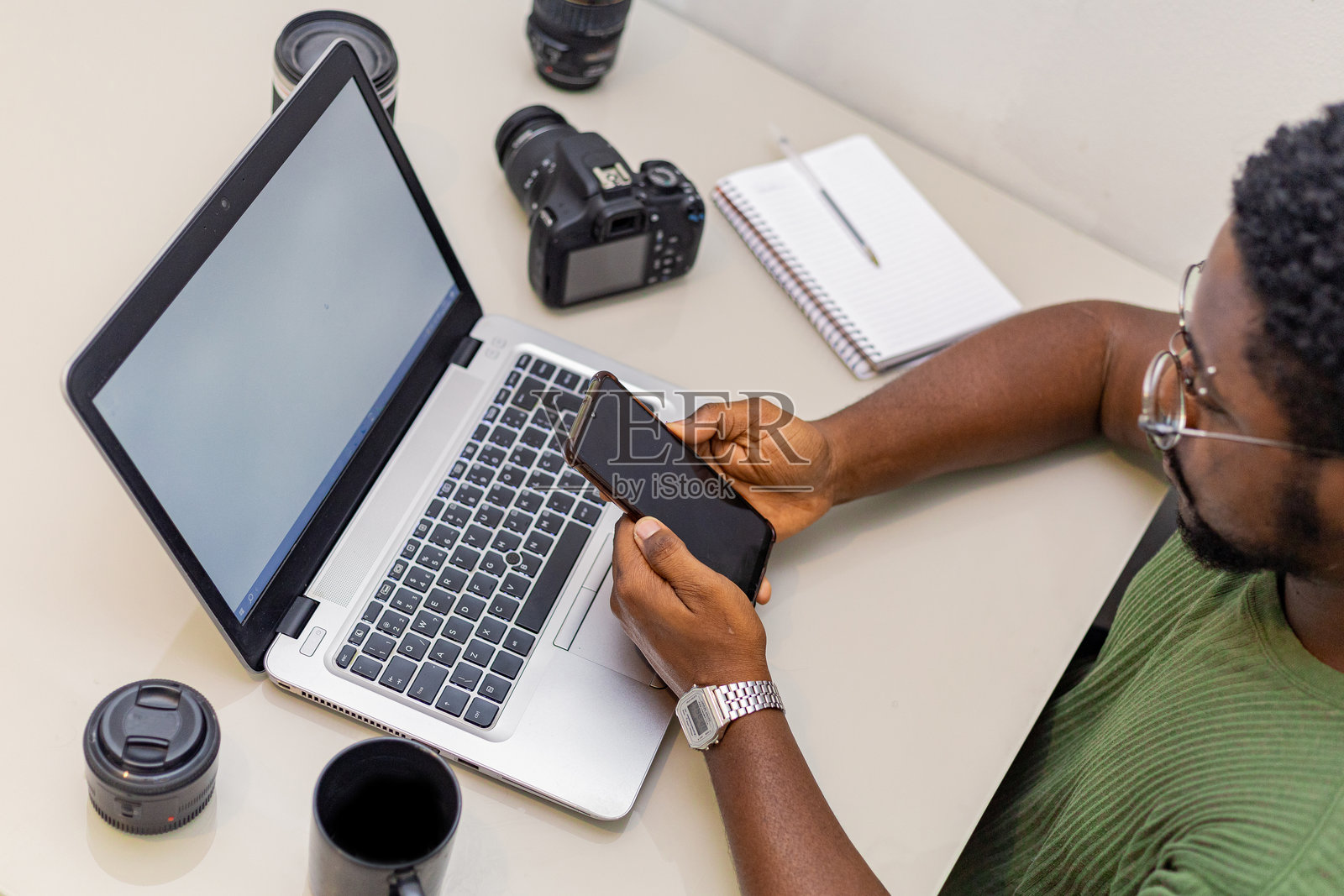 摄影师在使用笔记本电脑和数码相机。专业记者或自由职业者在桌子上使用笔记本与单反相机和摄影设备。照片摄影图片