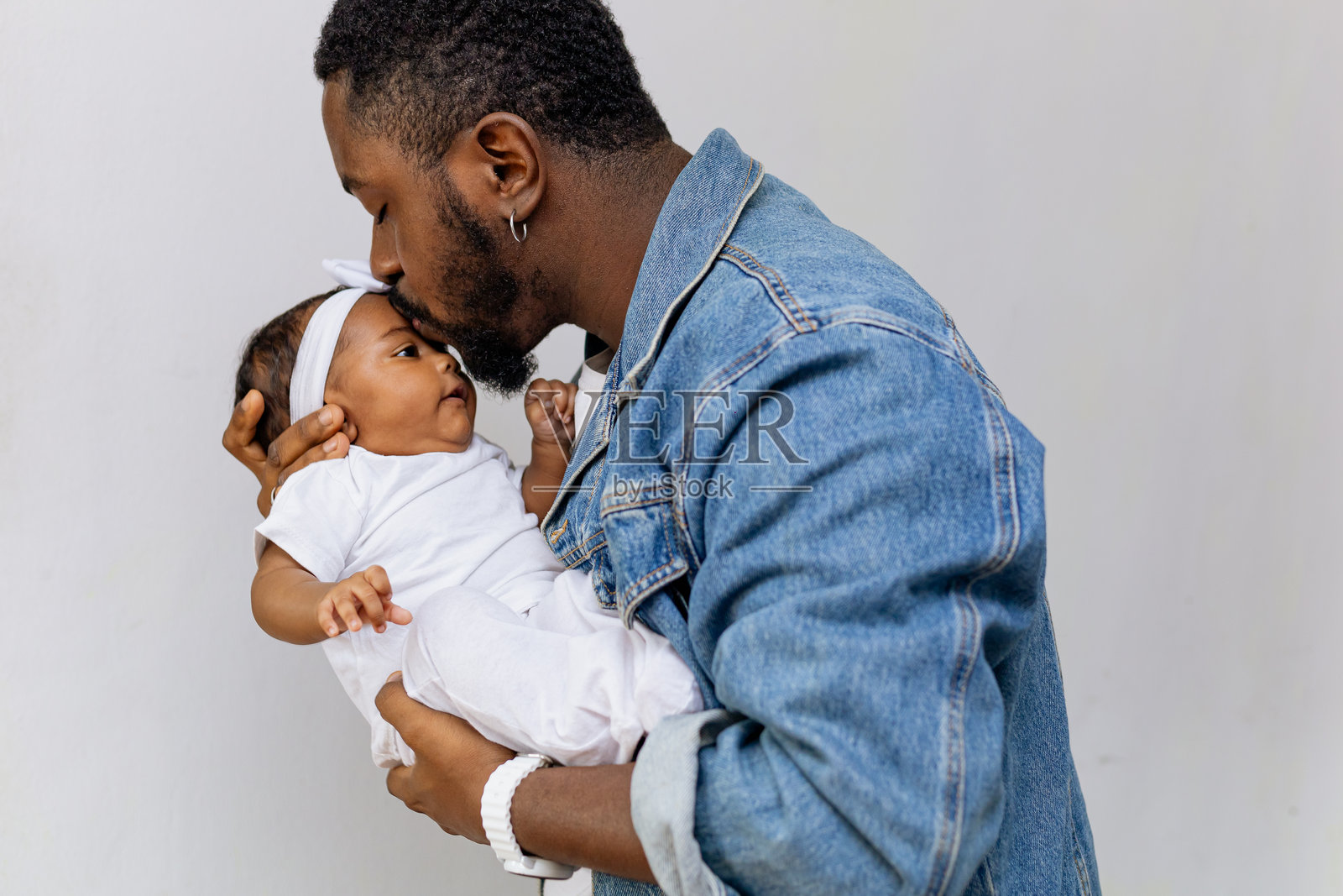 年轻父亲抱着并亲吻他美丽的新生女儿。父亲节。照片摄影图片