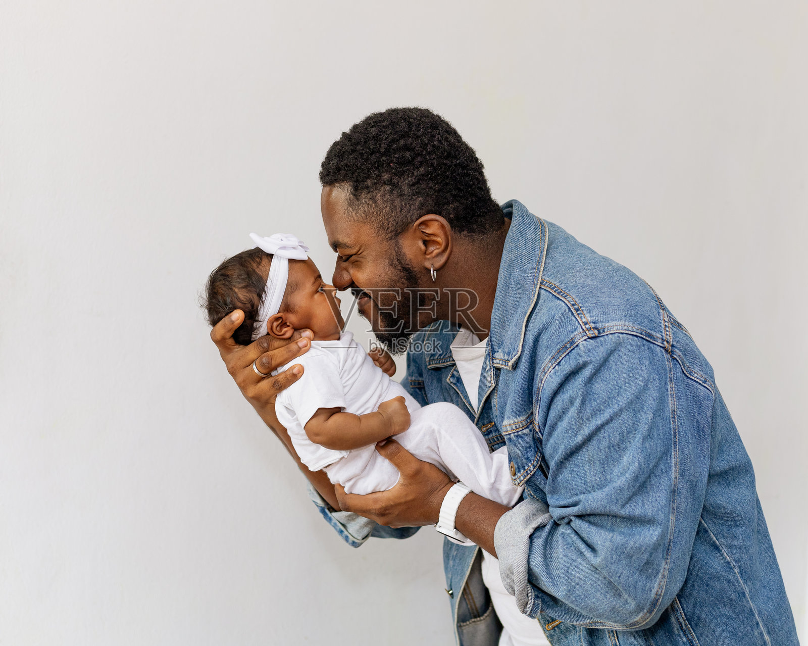 年轻父亲抱着并亲吻他美丽的新生女儿。父亲节。照片摄影图片