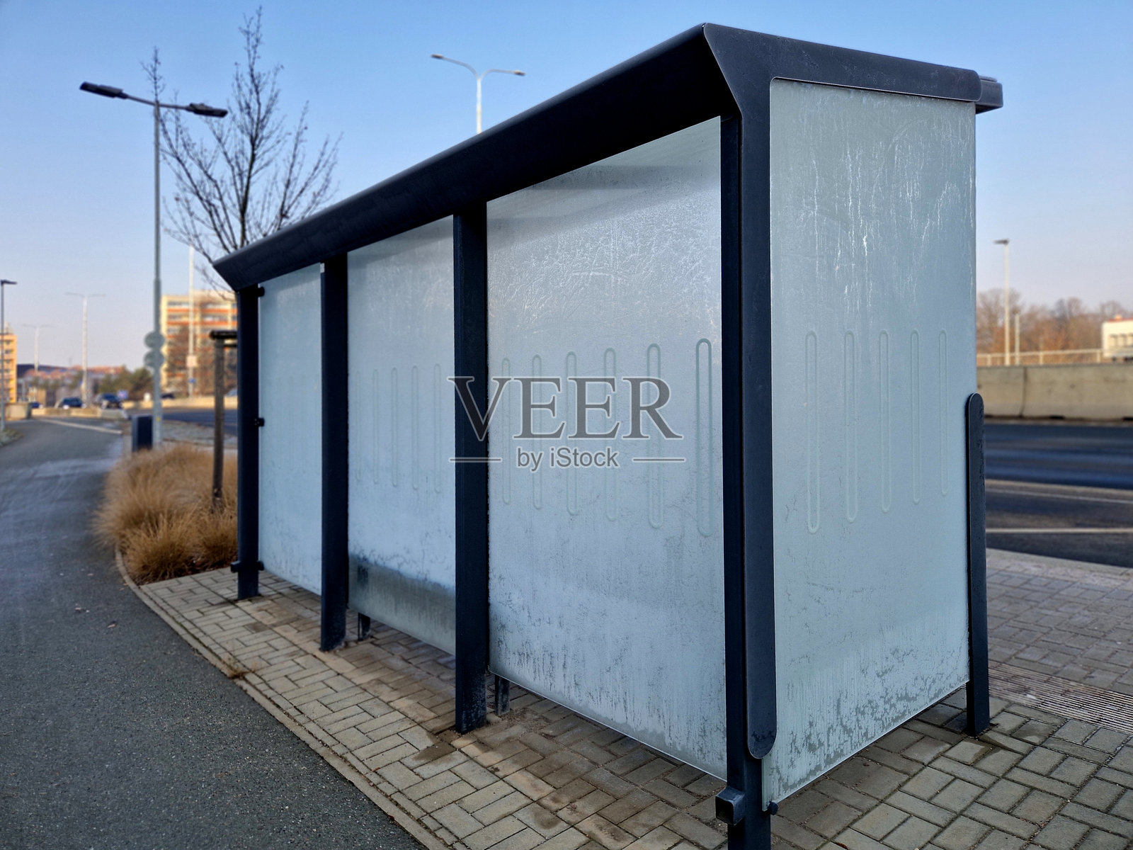 现代城市公交站的设计，座位和长椅，玻璃背面覆盖着清晨的新霜。玻璃板上的白霜。照片摄影图片