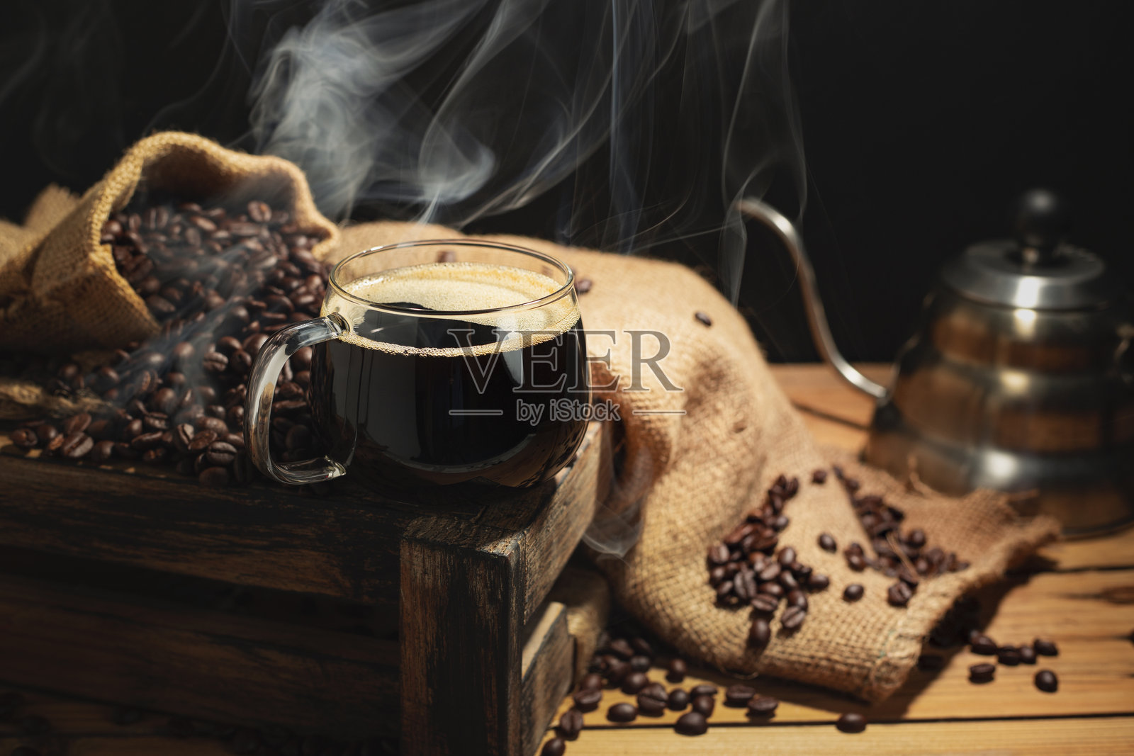 绿色咖啡杯里盛着热咖啡，烘焙咖啡豆在桌上排列，俯视图，黑色背景和深色调。照片摄影图片