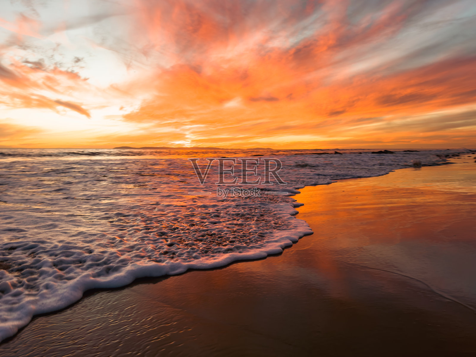 夕阳下海浪拍打着海岸照片摄影图片