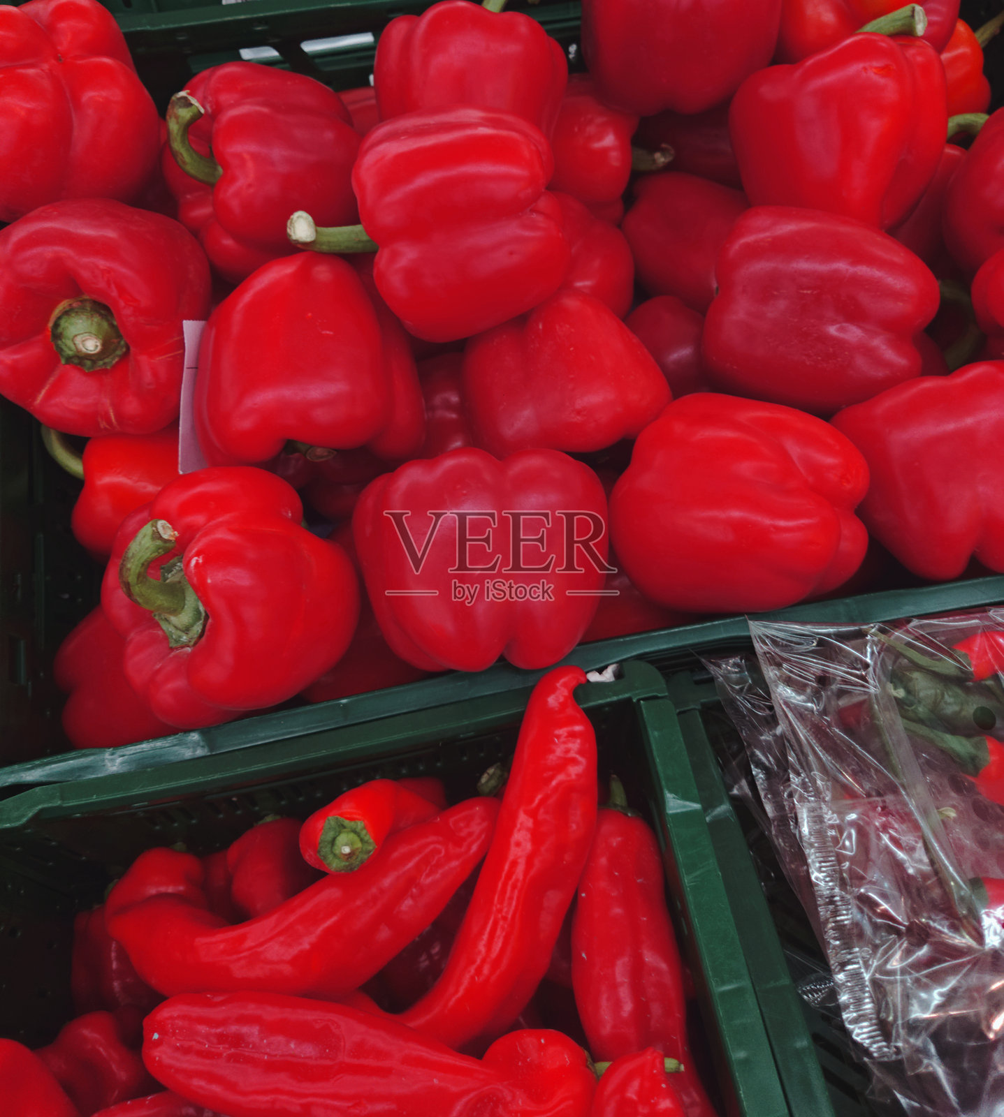 新鲜红色甜椒和长红辣椒的特写，放置在绿色塑料箱中。照片摄影图片