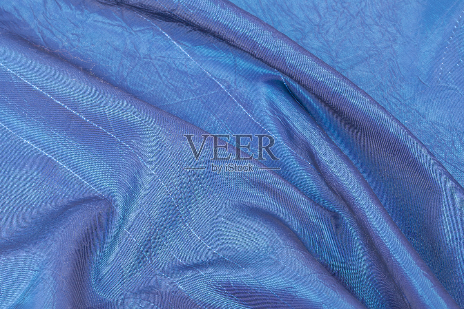 浅蓝色丝绸背景，光滑细腻的面料，带有不规则褶皱的特写。照片摄影图片