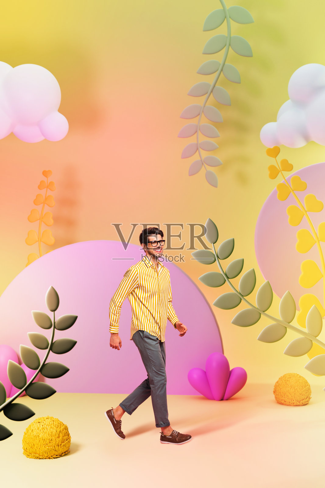 年轻积极的男子穿着条纹衬衫，走在温暖的装饰、草药和春天的云朵前，竖版照片拼贴，背景为涂鸦风格。照片摄影图片