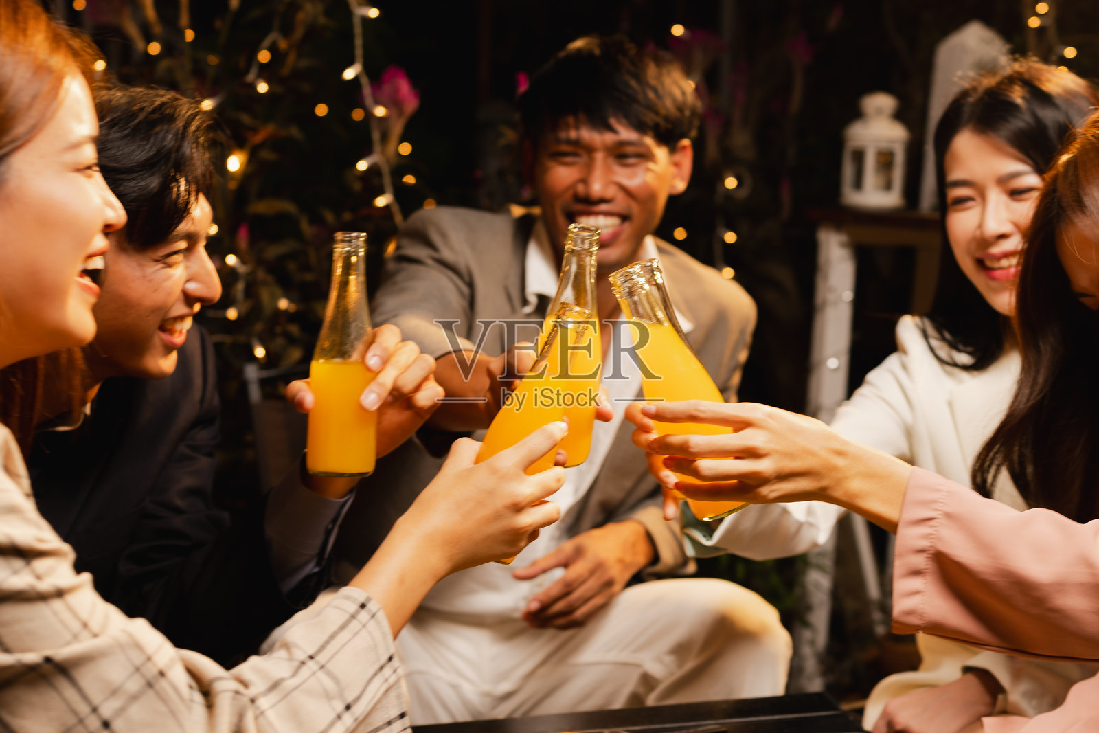 一群朋友在夜晚庆祝时碰杯。照片摄影图片
