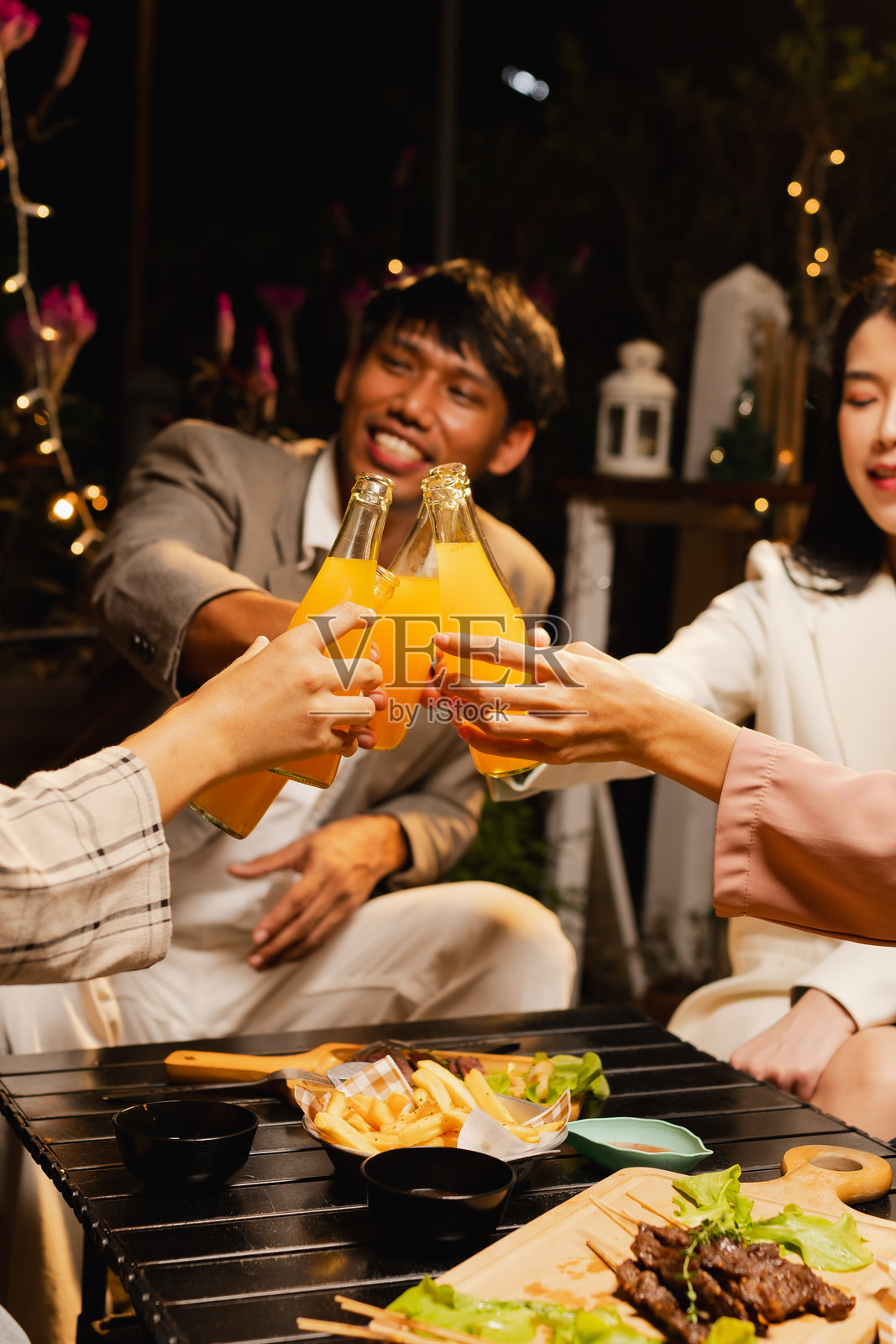 一群朋友在夜晚庆祝时碰杯。照片摄影图片